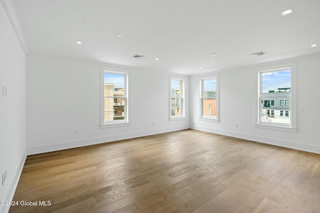 spare room with visible vents, crown molding, baseboards, and wood finished floors