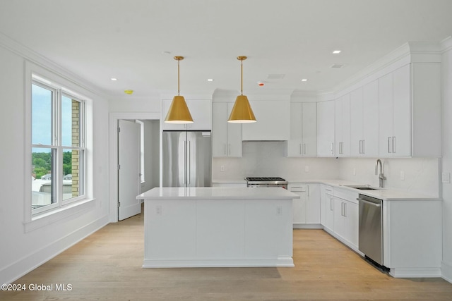 kitchen with a sink, a kitchen island, white cabinetry, stainless steel appliances, and light countertops