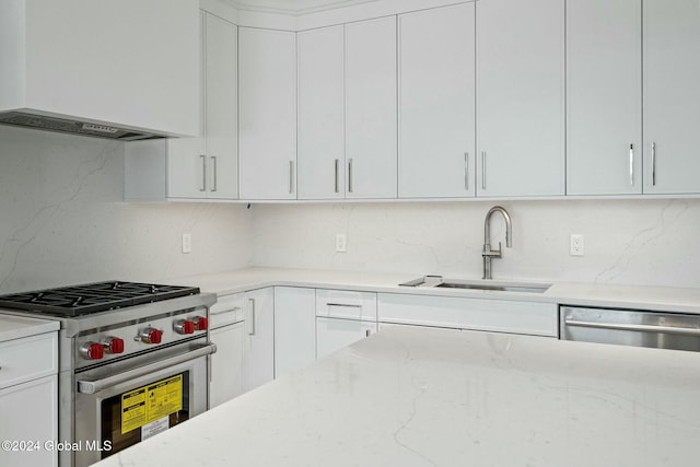 kitchen with a sink, light stone counters, appliances with stainless steel finishes, and white cabinetry