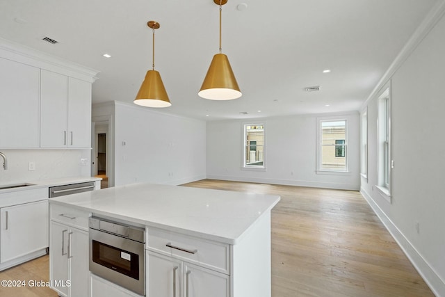 kitchen featuring a sink, visible vents, light wood-style floors, and ornamental molding