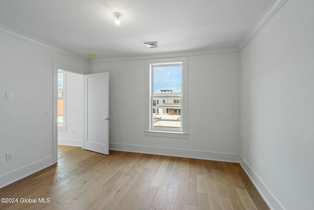 unfurnished room featuring baseboards, visible vents, light wood finished floors, and ornamental molding