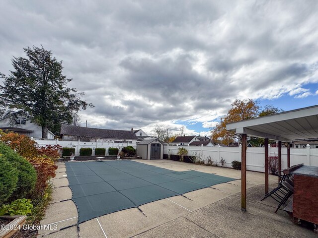 view of swimming pool with a shed and a patio