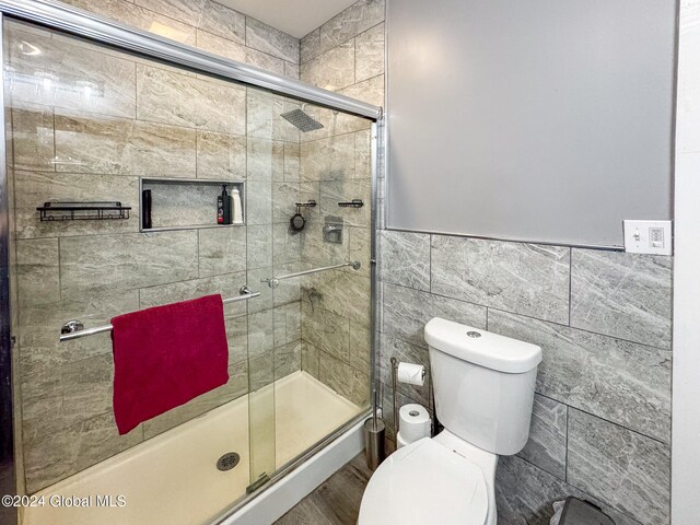 bathroom with toilet, tile walls, and walk in shower