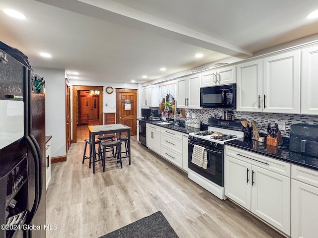 kitchen with black appliances, white cabinets, sink, dark stone countertops, and light wood-type flooring