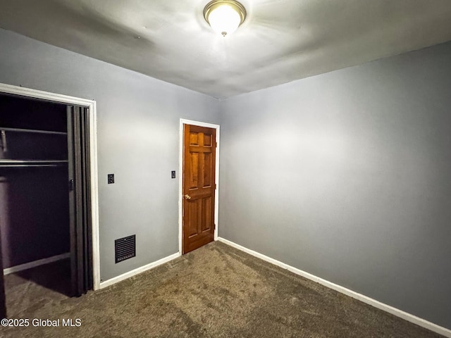 unfurnished bedroom with dark carpet and a closet