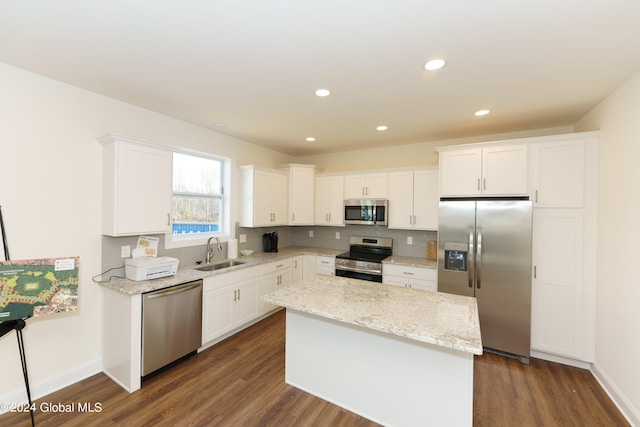 kitchen with sink, stainless steel appliances, light stone countertops, white cabinets, and a kitchen island