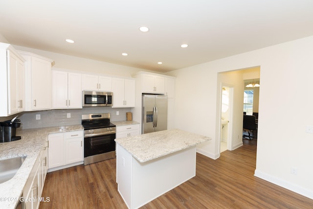 kitchen featuring a kitchen island, white cabinets, decorative backsplash, stainless steel appliances, and light stone countertops