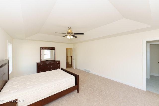 bedroom featuring light colored carpet, ceiling fan, and a tray ceiling