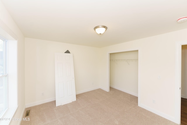 unfurnished bedroom with light carpet and a closet