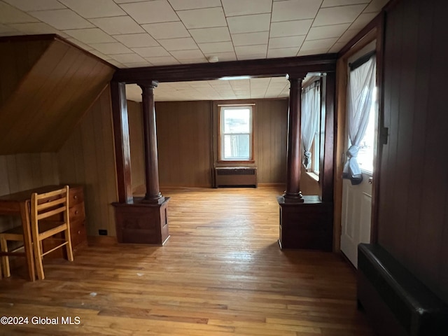 bonus room with radiator heating unit, lofted ceiling, wooden walls, and light hardwood / wood-style flooring