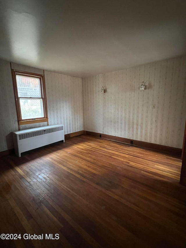 unfurnished room with radiator heating unit and dark hardwood / wood-style flooring