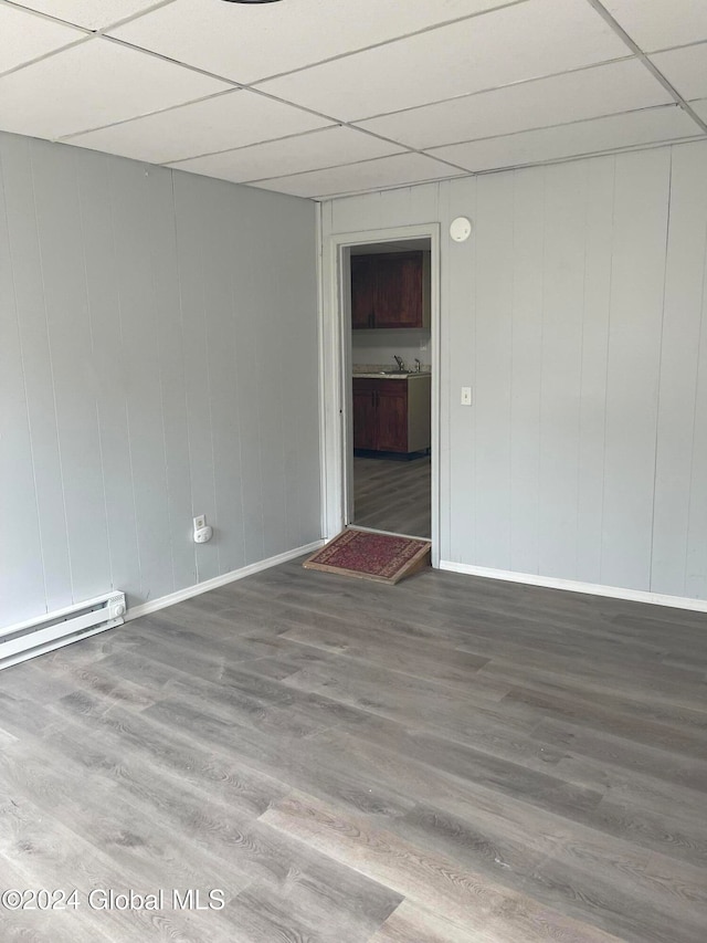 spare room with hardwood / wood-style flooring, a paneled ceiling, sink, and a baseboard radiator