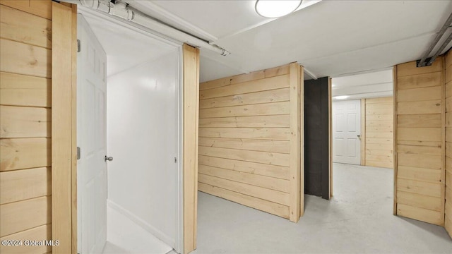 hallway featuring wood walls and concrete floors