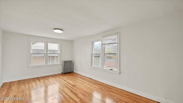 spare room with radiator heating unit and light hardwood / wood-style floors