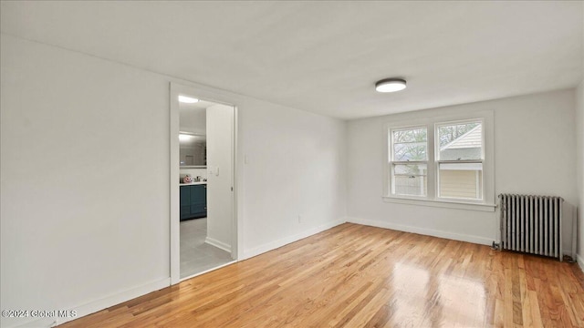 unfurnished room featuring radiator heating unit and light hardwood / wood-style flooring