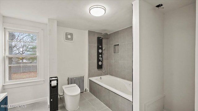 full bathroom featuring tile patterned flooring, tiled shower / bath, vanity, radiator heating unit, and toilet