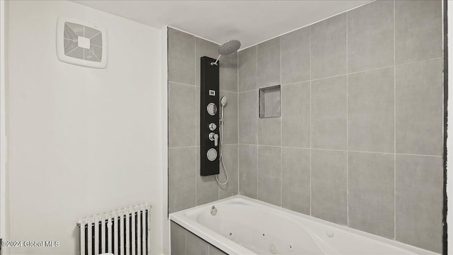 bathroom with radiator heating unit and tiled shower / bath combo