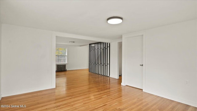 spare room with radiator heating unit and wood-type flooring