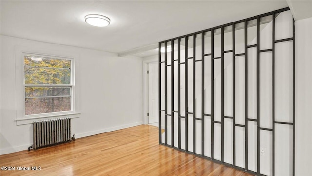 unfurnished room featuring hardwood / wood-style floors and radiator heating unit