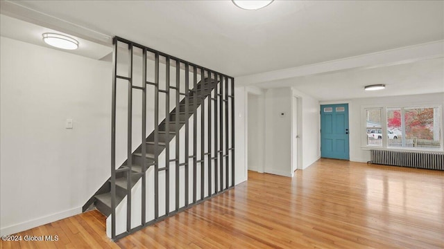 staircase with radiator heating unit and hardwood / wood-style flooring