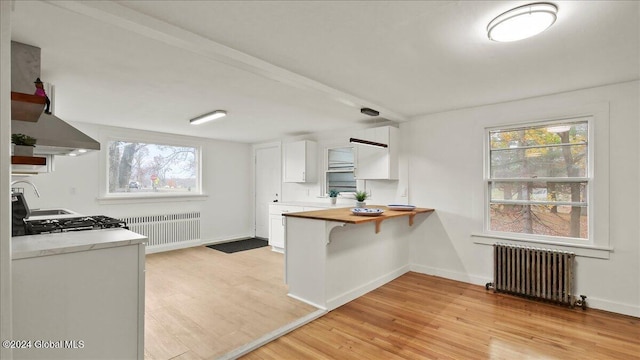 kitchen featuring white cabinets, radiator, wood counters, and light wood-type flooring