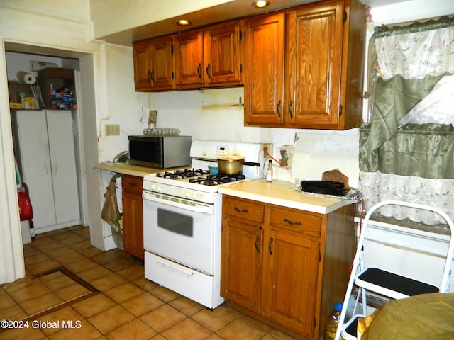 kitchen with white range with gas cooktop and light tile patterned floors