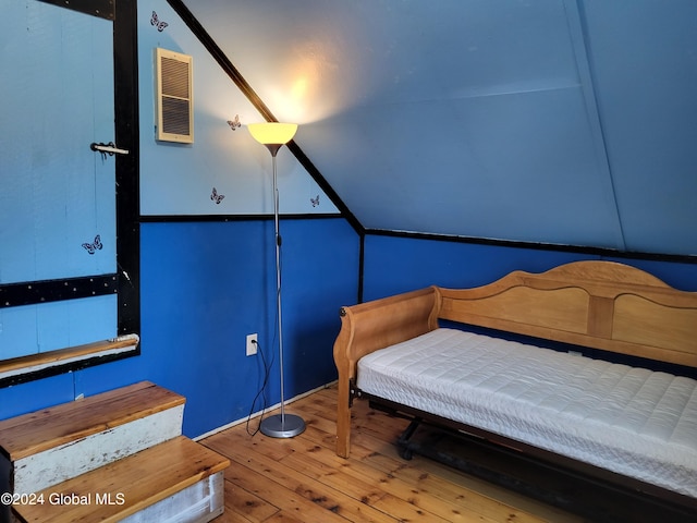 bedroom with wood-type flooring and vaulted ceiling