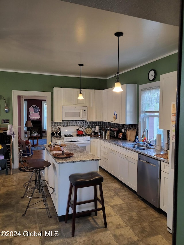 kitchen with white cabinets, a breakfast bar area, white appliances, and a kitchen island