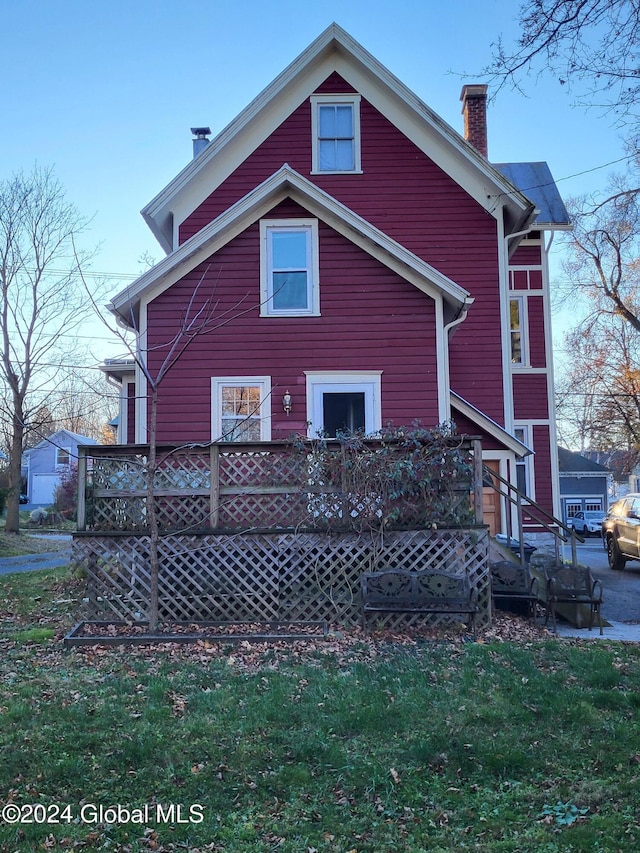 back of house featuring a lawn and a deck