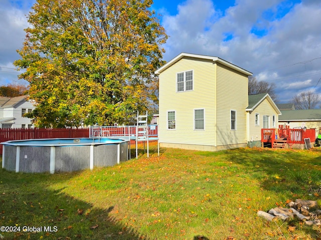 rear view of property with a pool side deck and a yard