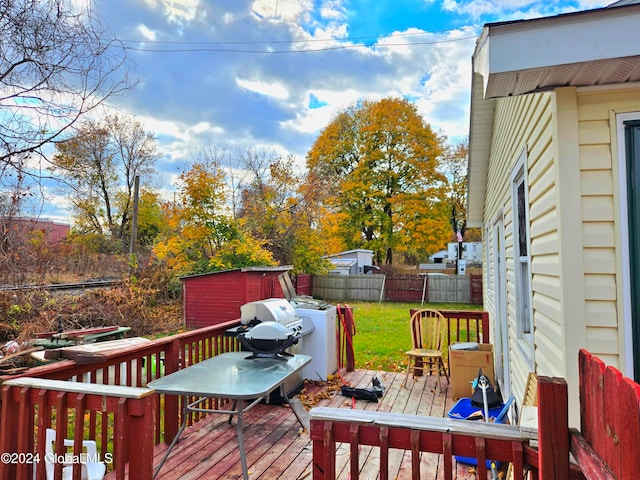 wooden terrace featuring washer / clothes dryer, a storage unit, and a lawn