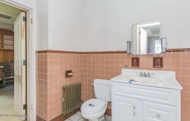 75 E Main St, Johnstown, NY 12095 - bathroom featuring radiator heating unit, tile walls, vanity, and wainscoting