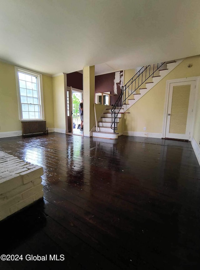 75 E Main St, Johnstown, NY 12095 - unfurnished living room featuring radiator heating unit, hardwood / wood-style floors, and stairs