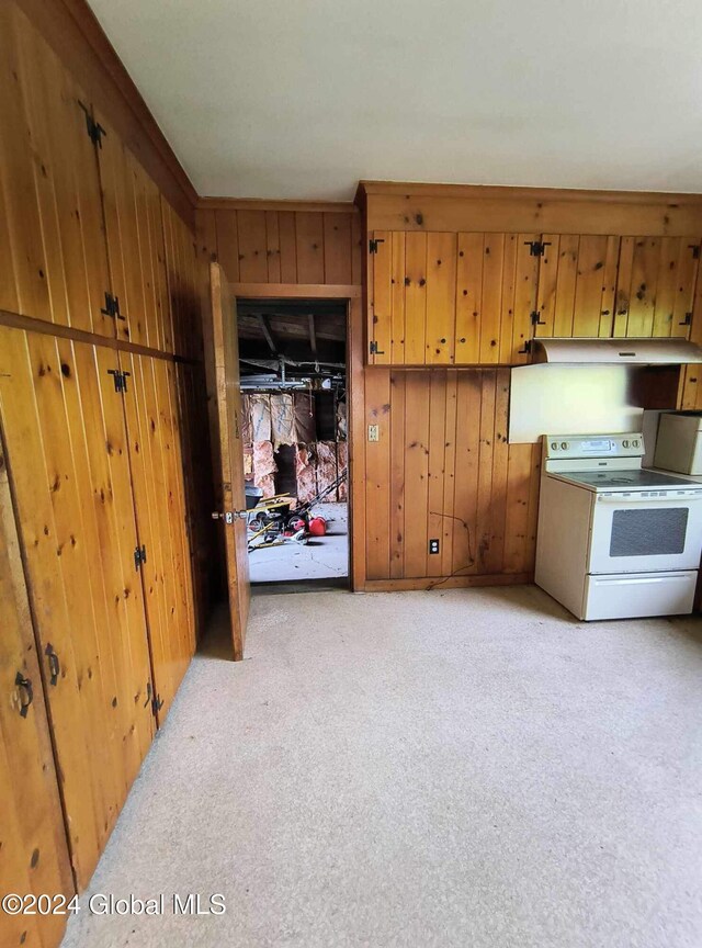 75 E Main St, Johnstown, NY 12095 - kitchen featuring white range with electric stovetop, wood walls, light carpet, ventilation hood, and brown cabinets
