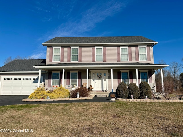 view of front facade featuring covered porch, a garage, and a front lawn