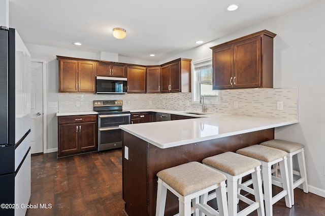 kitchen featuring appliances with stainless steel finishes, a kitchen breakfast bar, kitchen peninsula, and sink