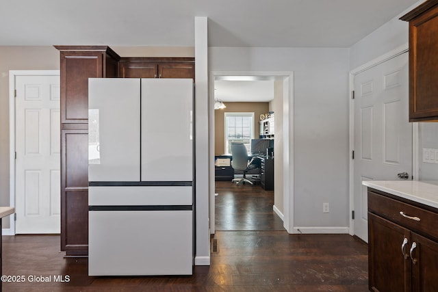 kitchen with dark brown cabinets, dark wood-type flooring, and white refrigerator