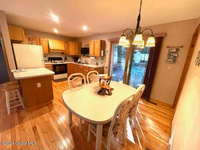 dining space with light hardwood / wood-style floors, sink, and an inviting chandelier