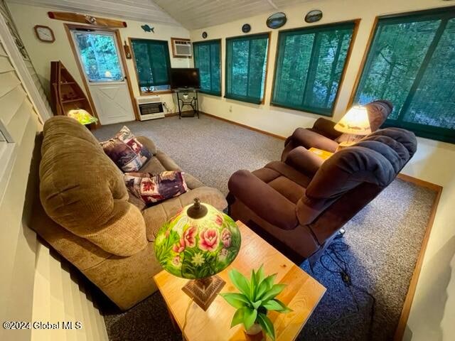 living room featuring lofted ceiling, a wall unit AC, and carpet flooring