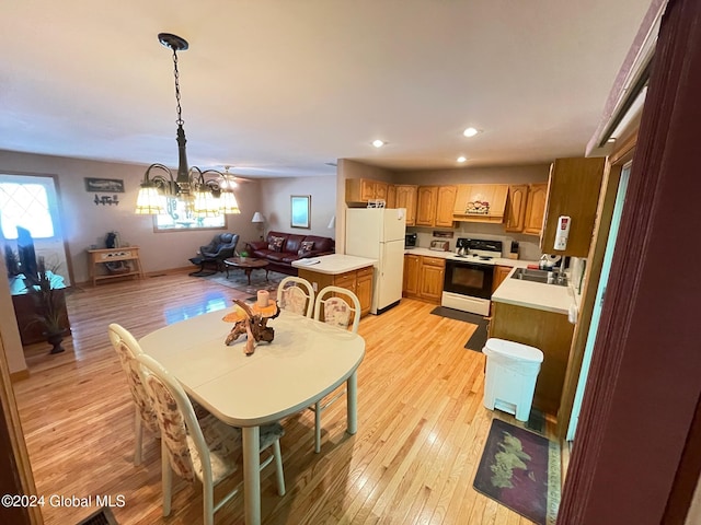 dining room with an inviting chandelier, sink, and light wood-type flooring