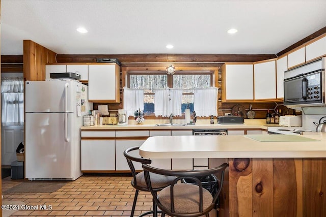 kitchen with backsplash, a breakfast bar, sink, white refrigerator, and white cabinets