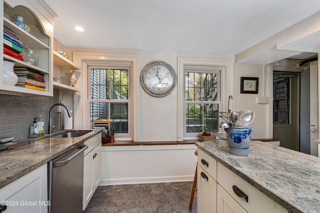 kitchen featuring decorative backsplash, stainless steel dishwasher, light stone counters, sink, and white cabinets