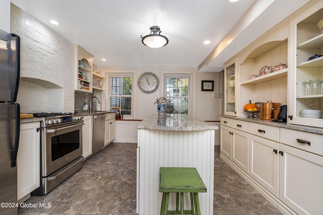 kitchen with light stone counters, a center island, stainless steel appliances, and sink