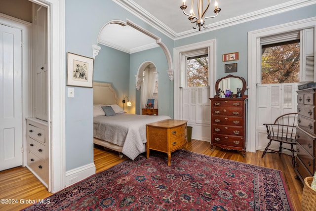 bedroom with hardwood / wood-style flooring, crown molding, and a notable chandelier