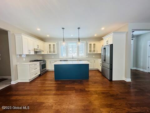 kitchen with stainless steel appliances, dark hardwood / wood-style flooring, white cabinets, and a kitchen island