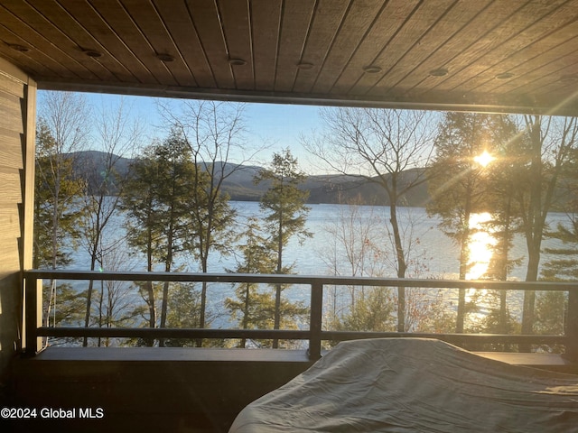 unfurnished bedroom featuring a water view, multiple windows, and wooden ceiling