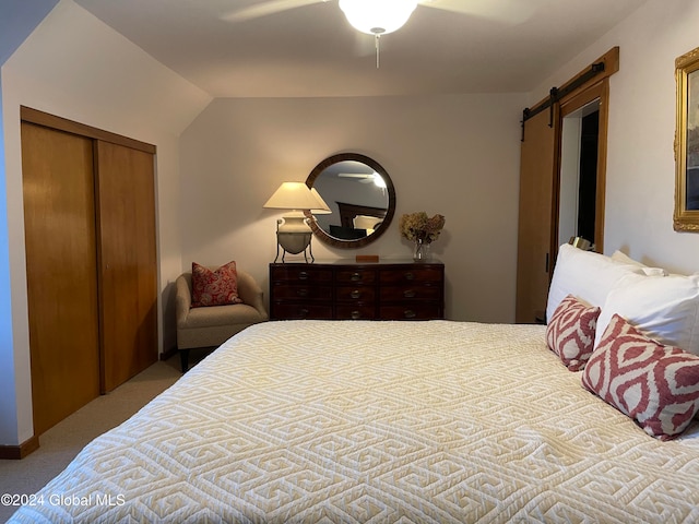 carpeted bedroom with ceiling fan, a barn door, lofted ceiling, and a closet