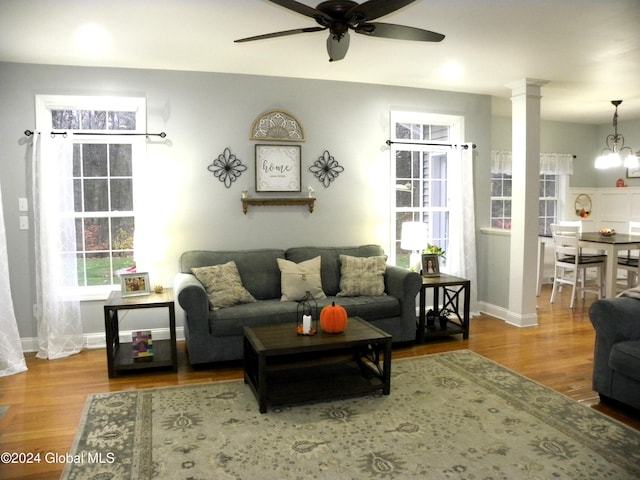 living room featuring hardwood / wood-style floors, ceiling fan with notable chandelier, and ornate columns