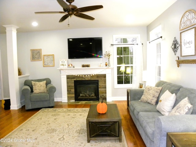 living room featuring ceiling fan, dark hardwood / wood-style flooring, and a fireplace