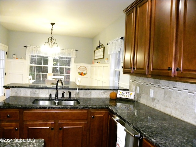 kitchen featuring sink, hanging light fixtures, an inviting chandelier, dark stone counters, and decorative backsplash